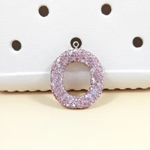 Détail d'un pendentif lettre O en cristaux roses utilisé comme breloque sur un sabot blanc