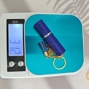 Detailed view of blue rhinestone perfume bottle keychain with leather tassel on scale