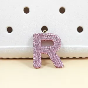 Vue macro du pendentif lettre R incrusté de strass roses avec anneau en métal doré