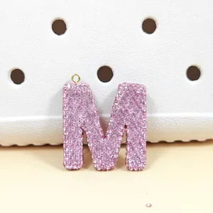 Vue macro d'un pendentif lettre M rose avec strass brillants et anneau doré
