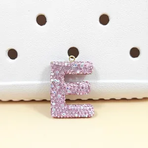 Gros plan détaillé du pendentif lettre E en strass rose avec anneau doré et effet brillant