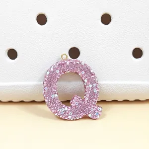 Vue macro du pendentif lettre Q en strass rose avec anneau doré sur une surface