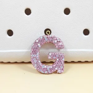 Détail du pendentif lettre G en strass rose avec anneau métallique doré brillant