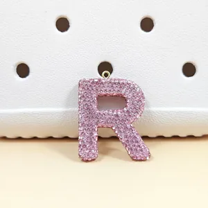 Vue détaillée du pendentif lettre R en strass roses avec anneau en métal doré