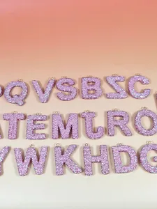 Porte-clés lettres en strass rose étincelants avec anneaux dorés sur fond dégradé doux