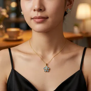 Elegant gold flower necklace and earrings set with light blue stones on a model