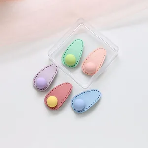Détail de cinq barrettes gouttes aux couleurs macaron avec coutures et perles mates