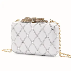 Macro shot of silver satin evening bag featuring rhinestone quilting and gold bow clasp