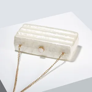 Close-up of marble texture acrylic clutch bag with gold round clasp and chain strap