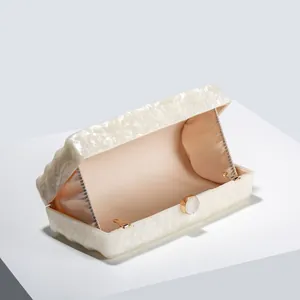 Detail of white marble acrylic evening clutch bag with gold hardware and pink satin lining