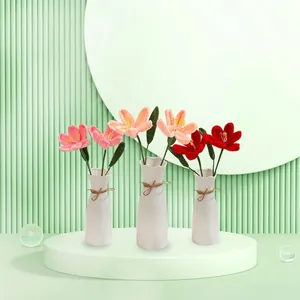 Handmade crochet tulips in ceramic vases featuring pink and red yarn flowers for home decor