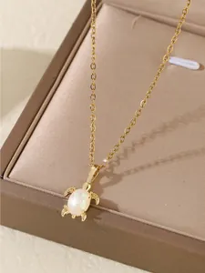 Gros plan d'un pendentif tortue dorée avec opale blanche sur un support en soie
