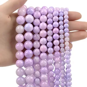 Close-up of polished purple round semi-precious stone beads in various sizes on hand