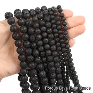 Close-up of matte black porous lava stone round beads held in hand for DIY jewelry