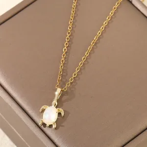 Collier pendentif tortue marine dorée avec opale blanche sur une boîte à bijoux