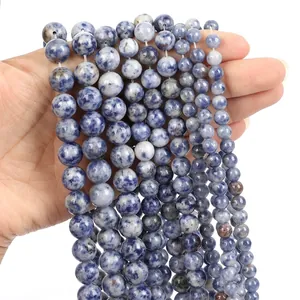 Macro detail of blue and white sodalite gemstone beads in various sizes on a white surface