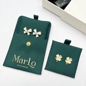 Detail of clover earrings and bow studs with luxury green microfiber jewelry pouches