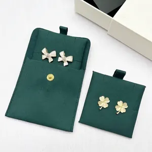 Detail of clover earrings and bow studs with luxury green microfiber jewelry pouches