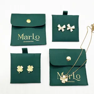 Macro detail of gold bow and clover jewelry set with dark green velvet pouches
