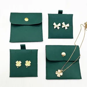 Macro detail of gold bow and clover jewelry set with dark green velvet pouches