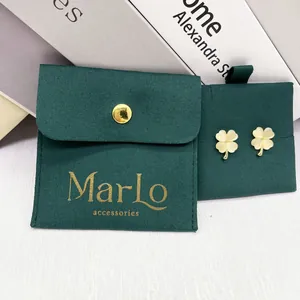 Detail of clover earrings with gold edges paired with a dark green velvet jewelry pouch