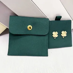 Detail of clover earrings with gold edges paired with a dark green velvet jewelry pouch