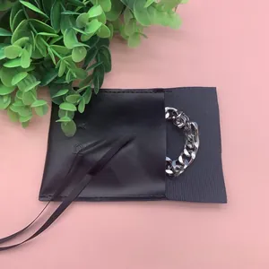 Silver Cuban chain bracelet partially shown inside a black microfiber jewelry pouch