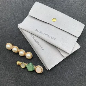 Detail of grey microfibre jewelry pouch with gold button and two decorative hair clips