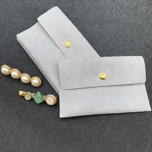 Detailed view of gray microfiber jewelry pouches with gold snaps and pearl hair clips