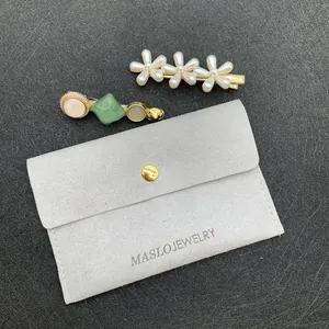 Close-up of pearl flower hair clips and resin star pins with a grey velvet jewelry bag