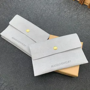 Detail of light gray microfiber jewelry pouches with gold metal snap and logo texture