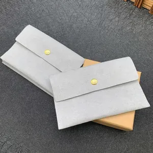 Detail of light gray microfiber jewelry pouches with gold metal snap and logo texture