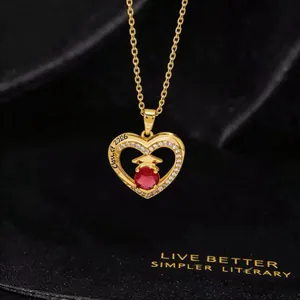 Close-up of golden graduation heart necklace with red stone and Class of 2026 engraving