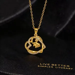 Macro view of gold heart necklace with mortarboard charm and engraved graduation quote