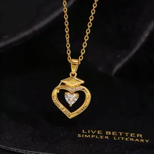 Detail of gold Class of 2026 graduation necklace with heart pendant and cap motif
