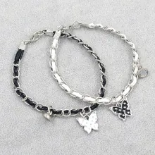Detail of woven leather chain bracelets with butterfly pendants in black and white
