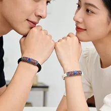 Close-up of braided leather bracelets with colorful enamel charms for couples