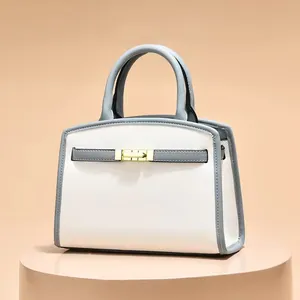 Elegant ivory and blue crossbody handbag with gold hardware and trapezoid design