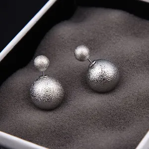 Détail macro de boucles d'oreilles double boule en argent avec texture mate sablée
