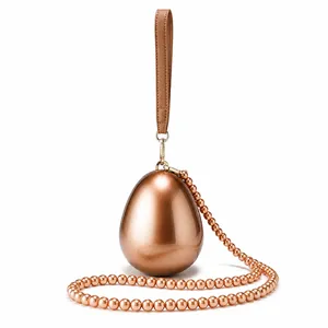 Detail of rose gold egg-shaped evening bag with beaded chain and leather wristlet strap