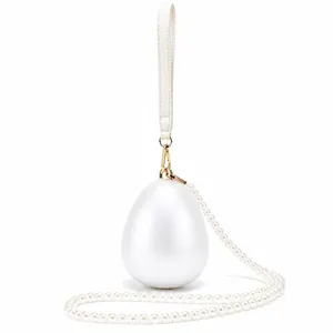 Detail of egg-shaped acrylic evening bag with pearl chain and golden metal clasp