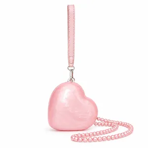 Pink heart-shaped shell evening clutch with decorative pearl chain and leather strap