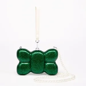 Detail of emerald green glitter shell bag with pearl chain and luxury acrylic finish