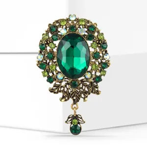Detail of baroque brooch with green oval crystal and emerald rhinestones on antique gold base