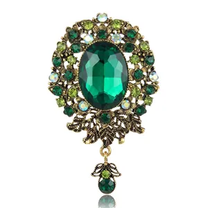 Vintage Baroque gold brooch with emerald green crystal and swinging leaf pendant detail