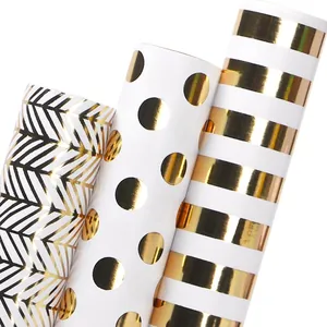 Three rolls of gold foil wrapping paper with dots, waves, and stripes for holidays