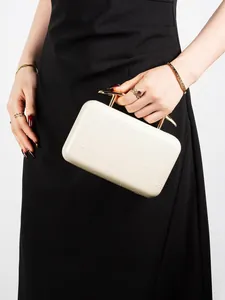 Close-up of creamy white evening bag with feather texture and golden metal handles