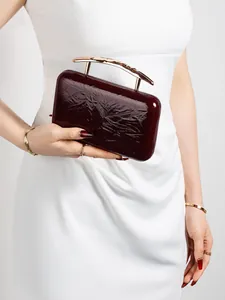 Macro shot of dark red embossed PU leather clutch with golden curved handle