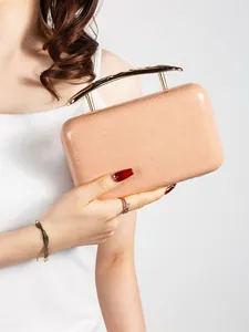 Detail view of pink pleated clutch bag with golden metal handle held by model