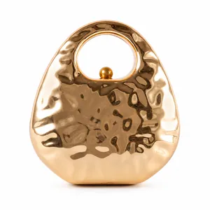 Macro detail of golden hard-shell evening clutch with unique metallic ripple texture